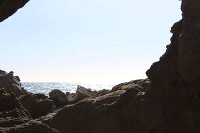 Rock formations by sea against clear sky