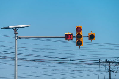 Low angle view of telephone pole against clear blue sky