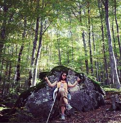 Woman standing on tree trunk in forest