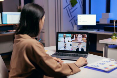 Rear view of woman using laptop on table