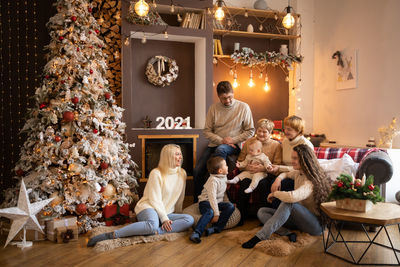 Cheerful family sitting at home by christmas tree