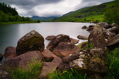 Rocks by lake against sky