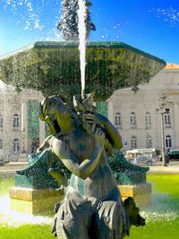 Statue by fountain against buildings