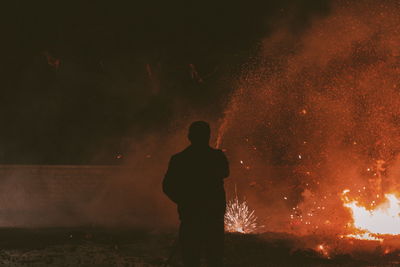 Rear view of silhouette man standing against fire