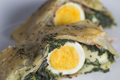 Two slices of puff pastry roll filled with spinach, cheese and hard-boiled egg,