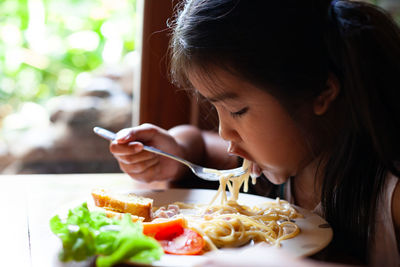 Girl having pasta at table