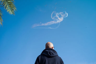 Low angle view of woman standing against blue sky