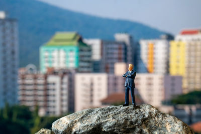 Man standing on rock against buildings in city