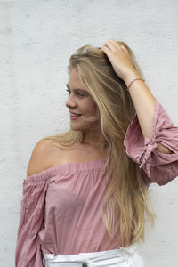 Portrait of beautiful woman standing against pink wall