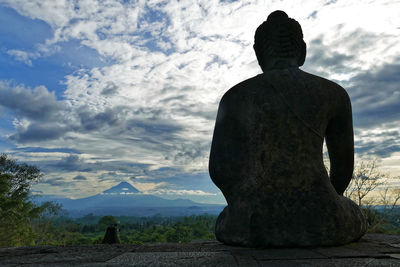Rear view of statue against cloudy sky