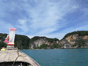 Scenic view of sea by mountain against sky