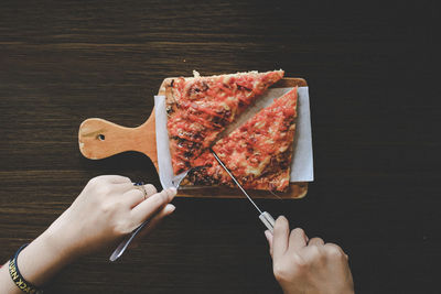 Cropped image of woman cutting sandwich on table