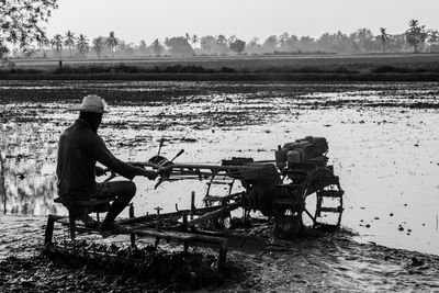 Side view of farmer using agricultural machinery while working at farm