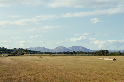 Hay bales on field against sky