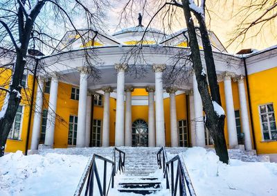 Snow covered bare trees against built structure in winter