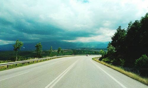 Empty road with trees in background