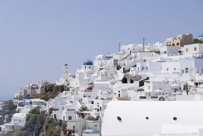 Whitewashed buildings in city against clear blue sky during sunny day