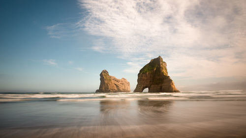 Rock formation on beach against sky