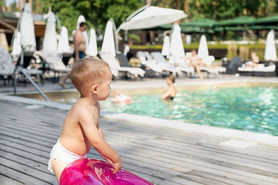 Side view of shirtless boy standing at poolside