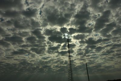 Low angle view of power lines against cloudy sky