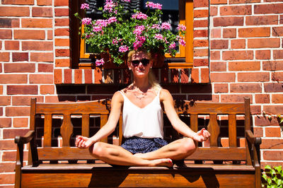 Portrait of young woman doing yoga while sitting on bench