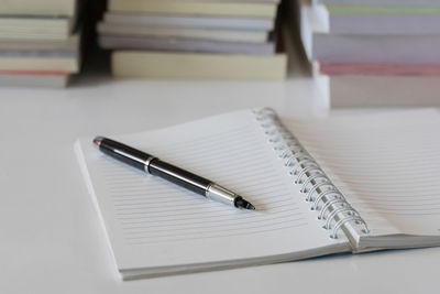 Close-up of pen on open blank book at table