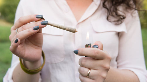 Midsection of woman lighting marijuana joint