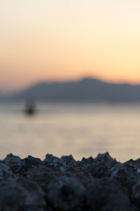 Rocks on beach against sky during sunset