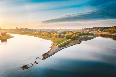 Aerial view of lake by townscape against sky