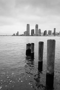 Wooden posts in sea against buildings in city