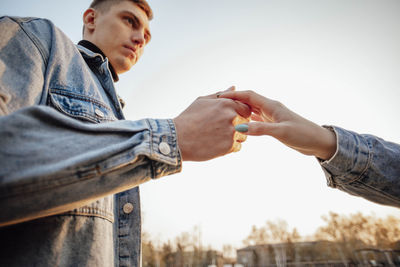 Hands of man and woman on blue sky background