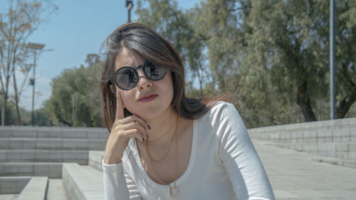Portrait of beautiful young woman wearing sunglasses in city during sunny day