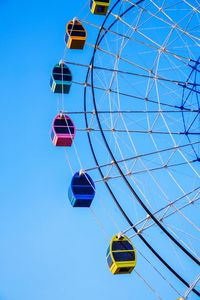 Low angle view of ferris wheel against clear blue sky