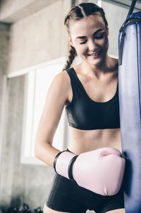 Smiling woman punching bag in gym