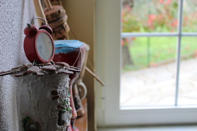 Close-up of old rusty clock by window at home