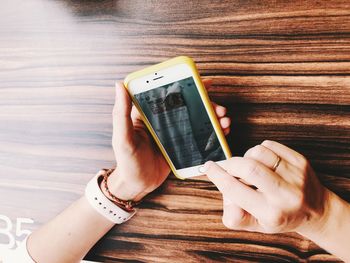 Midsection of man using mobile phone on table