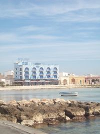 Buildings by sea against sky