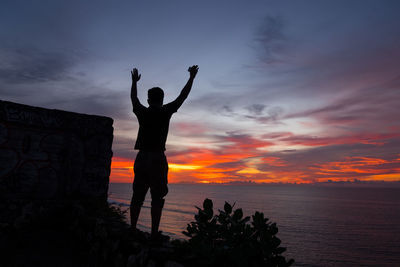 Silhouette man standing by sea against sky during sunset