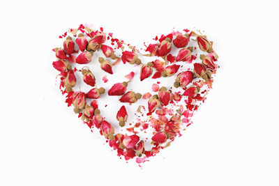 Close-up of heart shape with pink flowers against white background