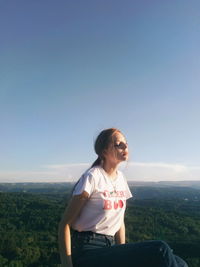 Young woman sitting against landscape