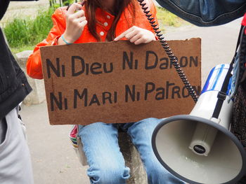 Midsection of people with information sign and megaphone on street