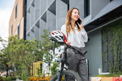 Portrait of young woman standing against building