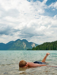 Rear view of woman swimming in sea against sky