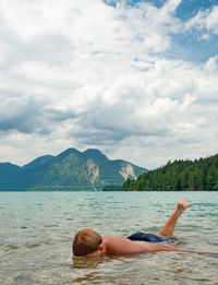 Young blond hair boy is swimming in mountain lake walchensee. scene with lake in bavaria germany