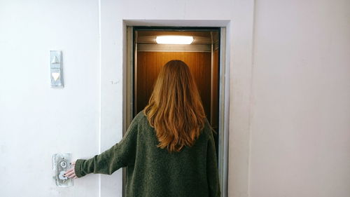 Rear view of woman against elevator in building