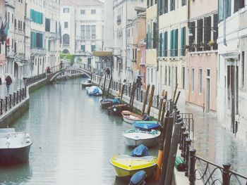 Boats moored in canal amidst buildings