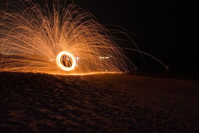 Illuminated wire wool at beach during night