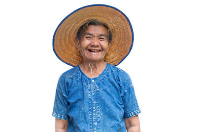 Portrait of happy senior woman wearing hat while standing against white background