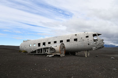 Abandoned airplane on airport runway against sky