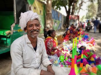 Portrait of smiling vendor selling toys at market stall